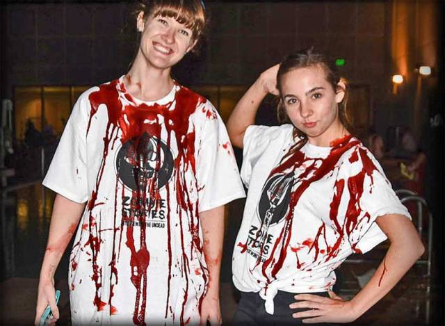 Two college students wearing Zombie Stories shirts, covered in fake blood.